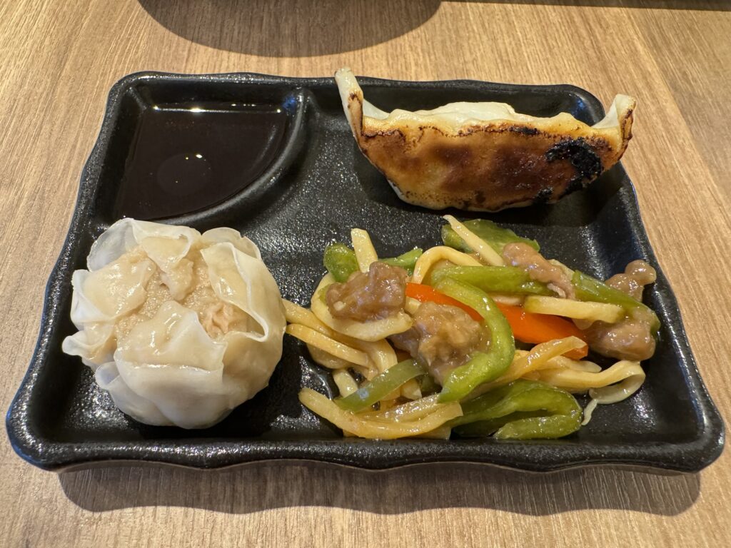 プレートに盛り付けられた大きな焼売、餃子、青椒肉絲の中華三点盛り