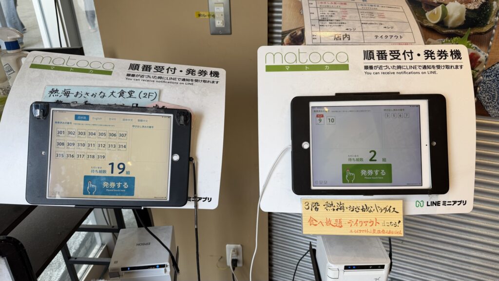 熱海おさかな・大食堂の店頭に設置されたLINE連携の順番受付システム「matoca」。10時過ぎで19組待ちを表示している液晶画面