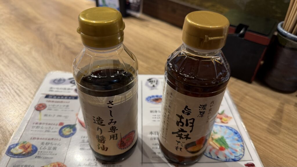 卓上に用意された「さしみ専用造り醤油」と「濃厚旨胡麻だれ」のボトル。