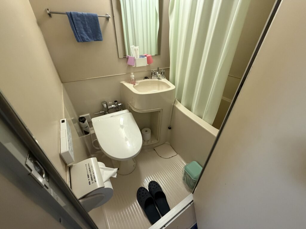 湯ーとぴあ420号室のユニットバス トイレと洗面が一体になった浴室とスリッパ