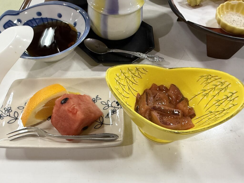 湯ーとぴあの夕食のデザート スイカと煮物が黄色い器に盛られている