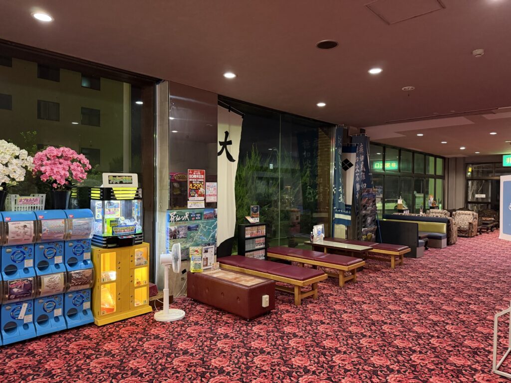 湯ーとぴあの休憩処 ベンチと自動販売機が並ぶ赤絨毯のロビー
