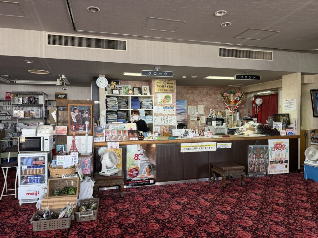 湯ーとぴあのフロントカウンター 木目の受付と土産物が並ぶ館内
