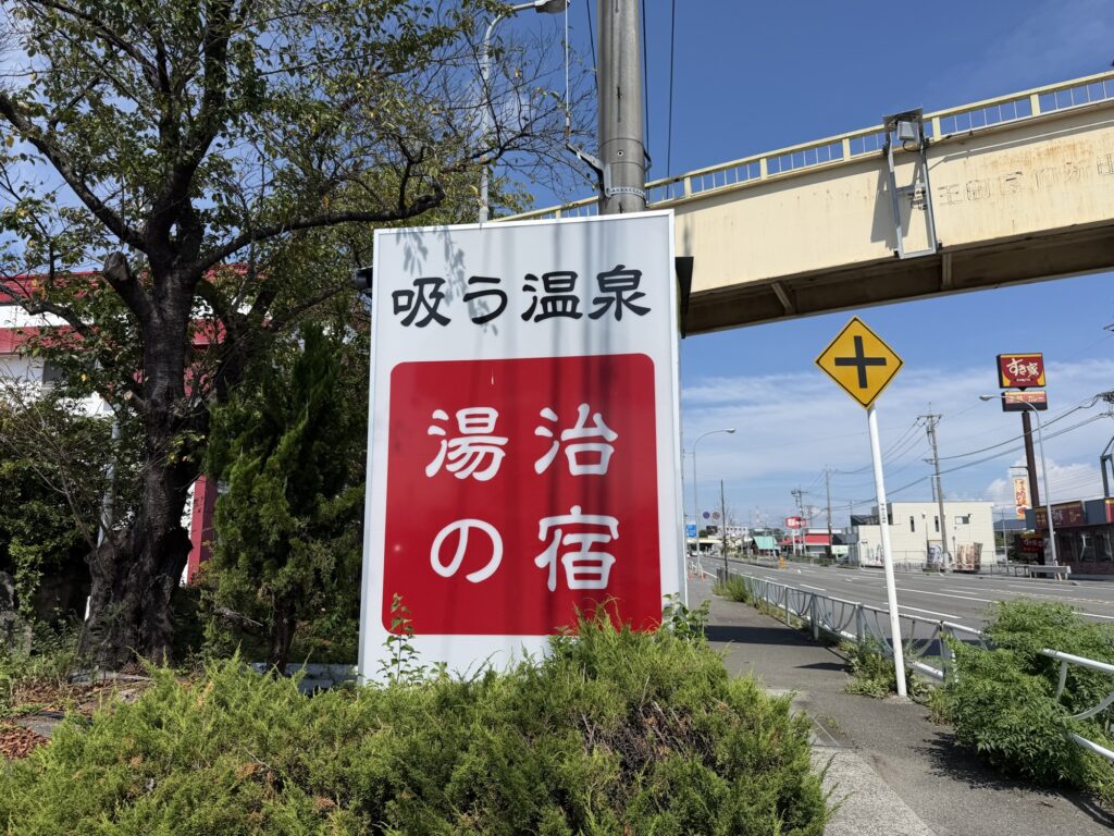 道路沿いに立つ「吸う温泉 湯治の宿」と書かれた湯ーとぴあの看板