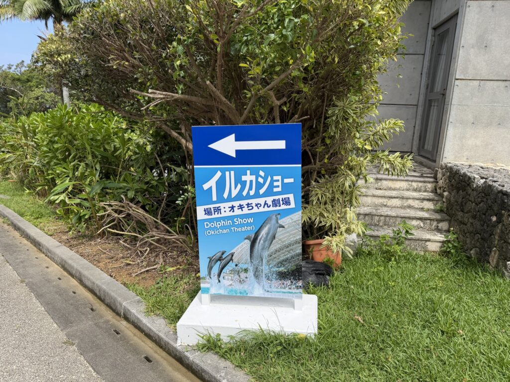 「イルカショー オキちゃん劇場」への案内看板、矢印付き